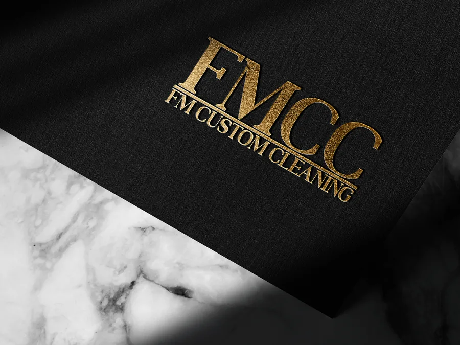 FMCC logo printed in gold foil on black paper resting on white marble