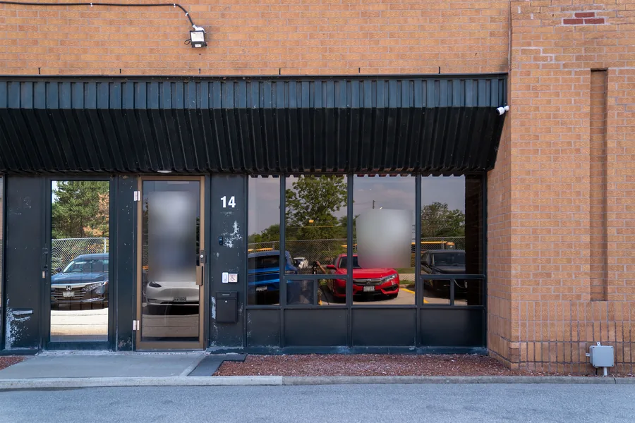 Brick commercial unit with a black metal awning over a glass entrance and windows