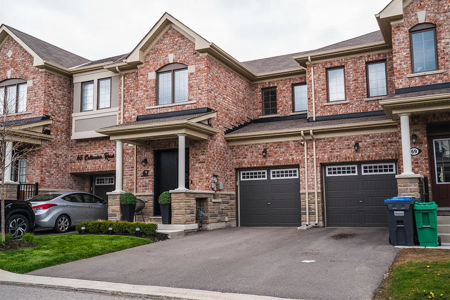 Front of a red brick townhouse row with double garages and a clear sky