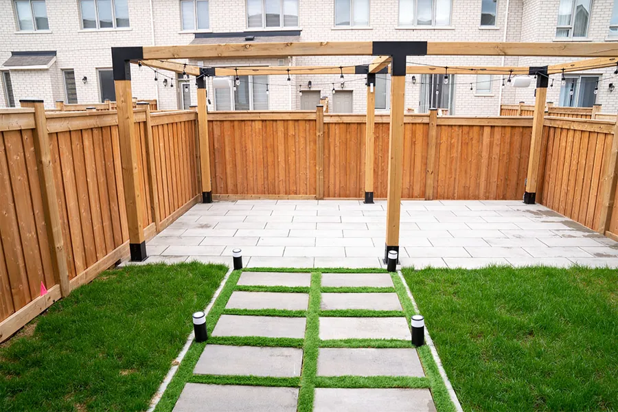 Fenced backyard with lawn, stepping stones and a wooden pergola