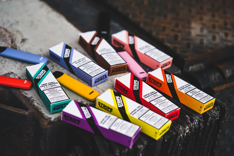 A pile of Stripe Disposable boxes and devices in every colour on a concrete ledge