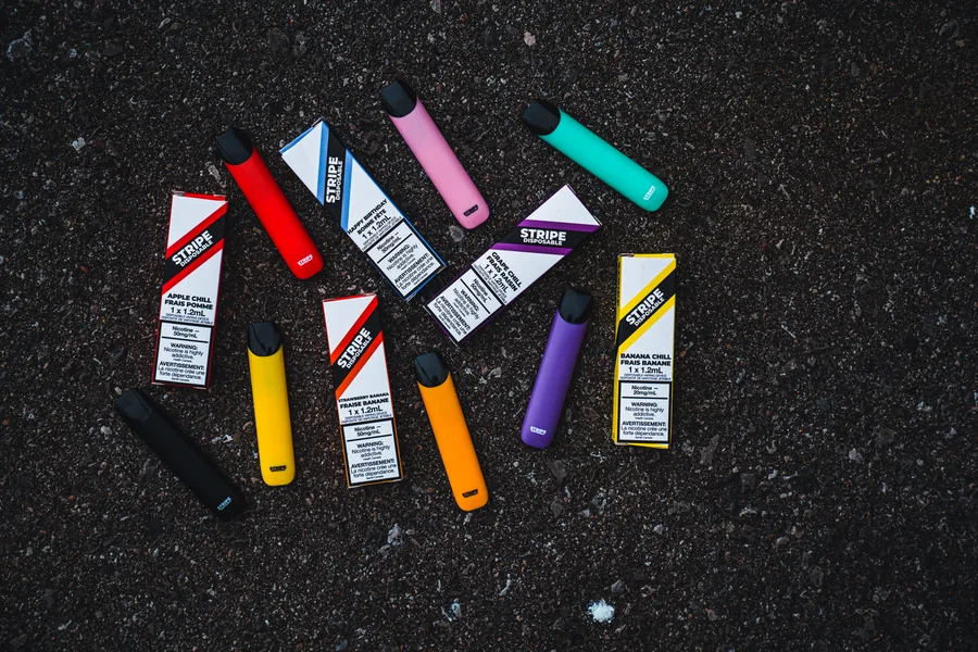 Stripe boxes and devices in many colours scattered on dark asphalt seen from above