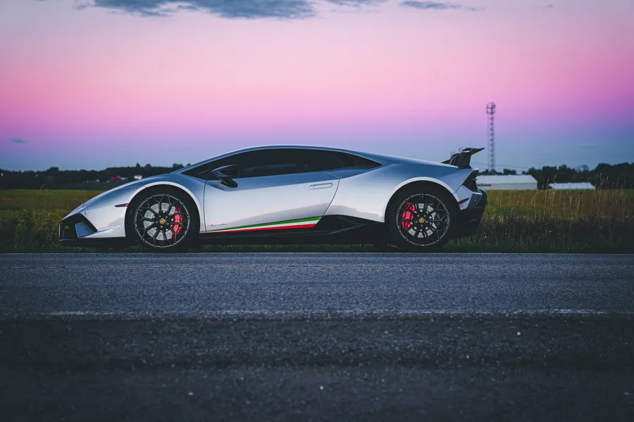 A silver Lamborghini Huracán Performante in full profile on an empty road under a pink and purple dusk sky
